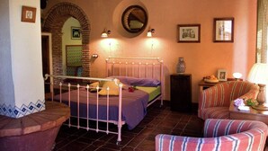 A bedroom with a bed, a chair, a small table, a mirror, and a picture on the wall. - El Búho, Cottage in Alájar (Alájar)