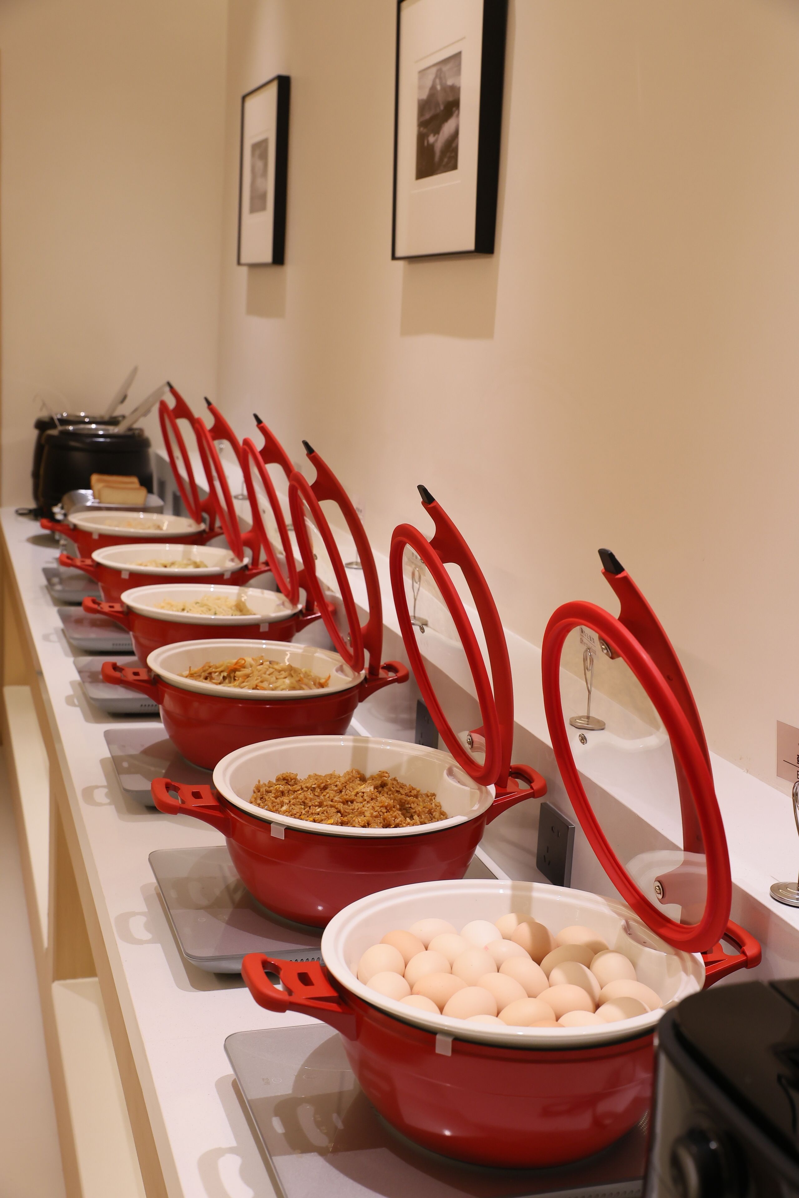 A buffet line with red serving dishes and a weighing scale.