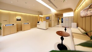 Un moderno vestíbulo de hotel con mostrador de recepción, zona de estar y una pantalla de televisión.