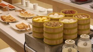 Un bufé con diversos alimentos, como dumplings, pasteles y salsas.