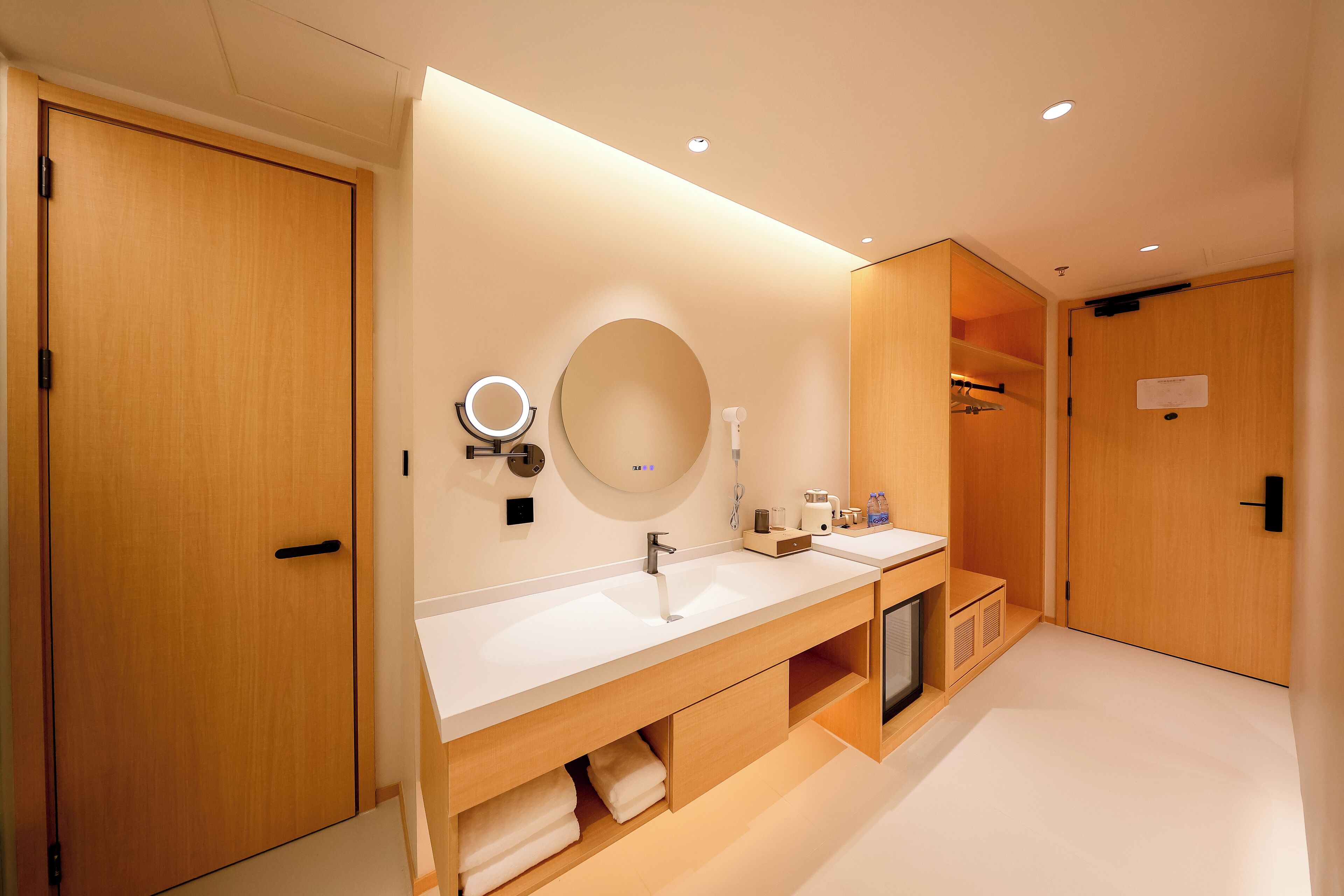 A modern bathroom with wooden cabinetry, a double sink vanity, and a mirror with integrated lighting.