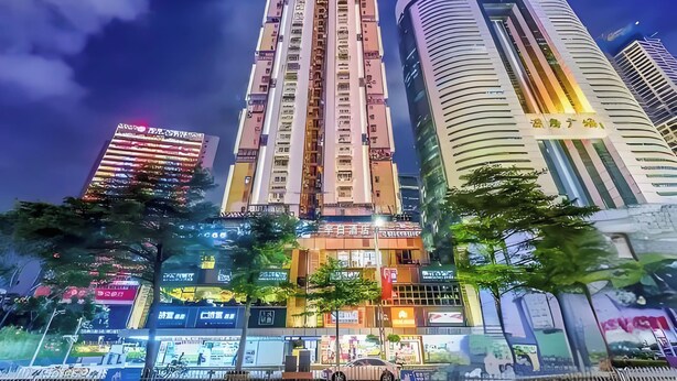 Un edificio de gran altura con varios pisos y balcones, rodeado de otros edificios altos.