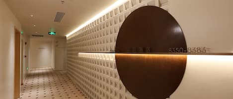 Un pasillo con suelo estampado, un letrero circular montado en la pared y un diseño de pared tipo entramado.