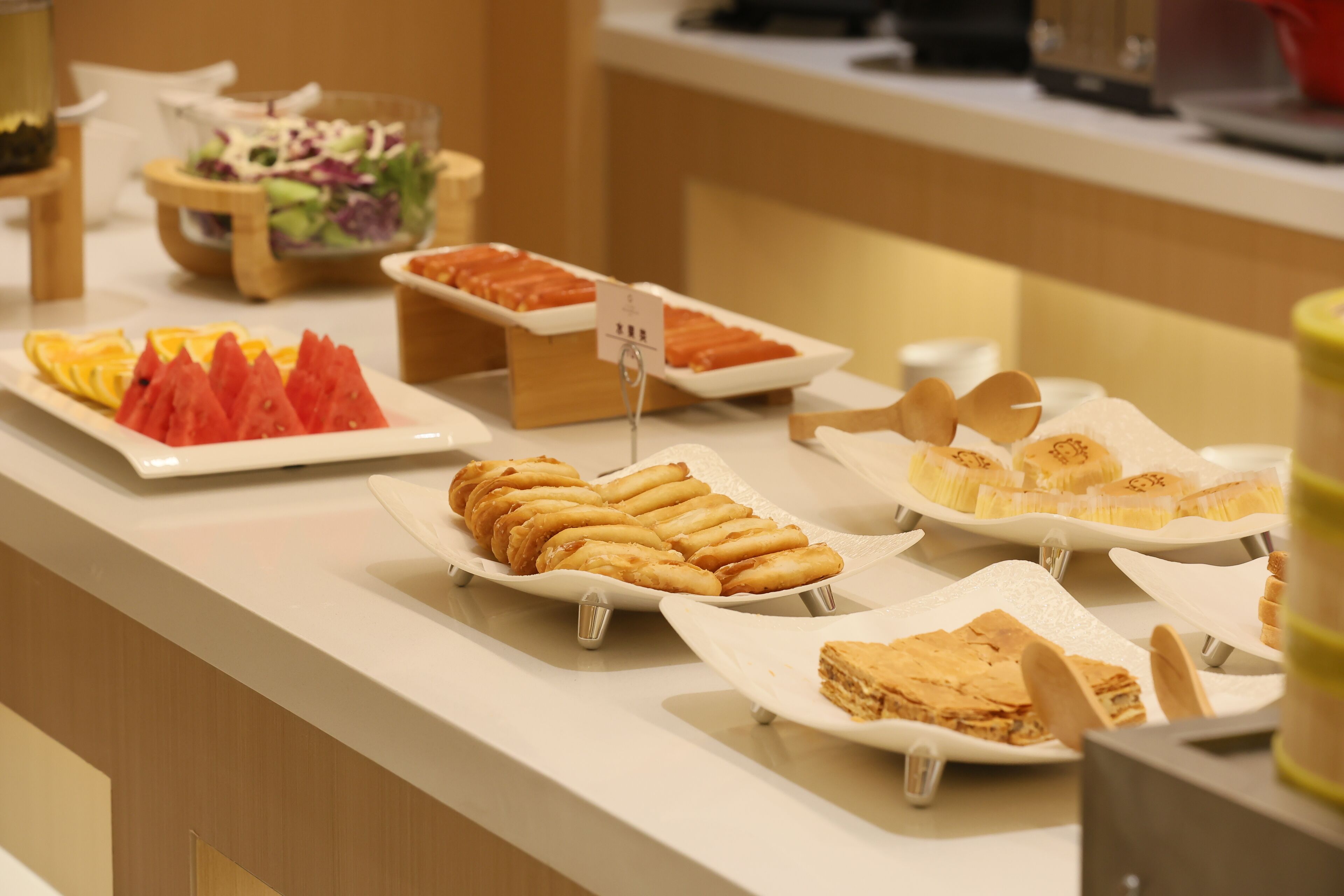 A buffet with various food items including fruits, pastries, and salads.