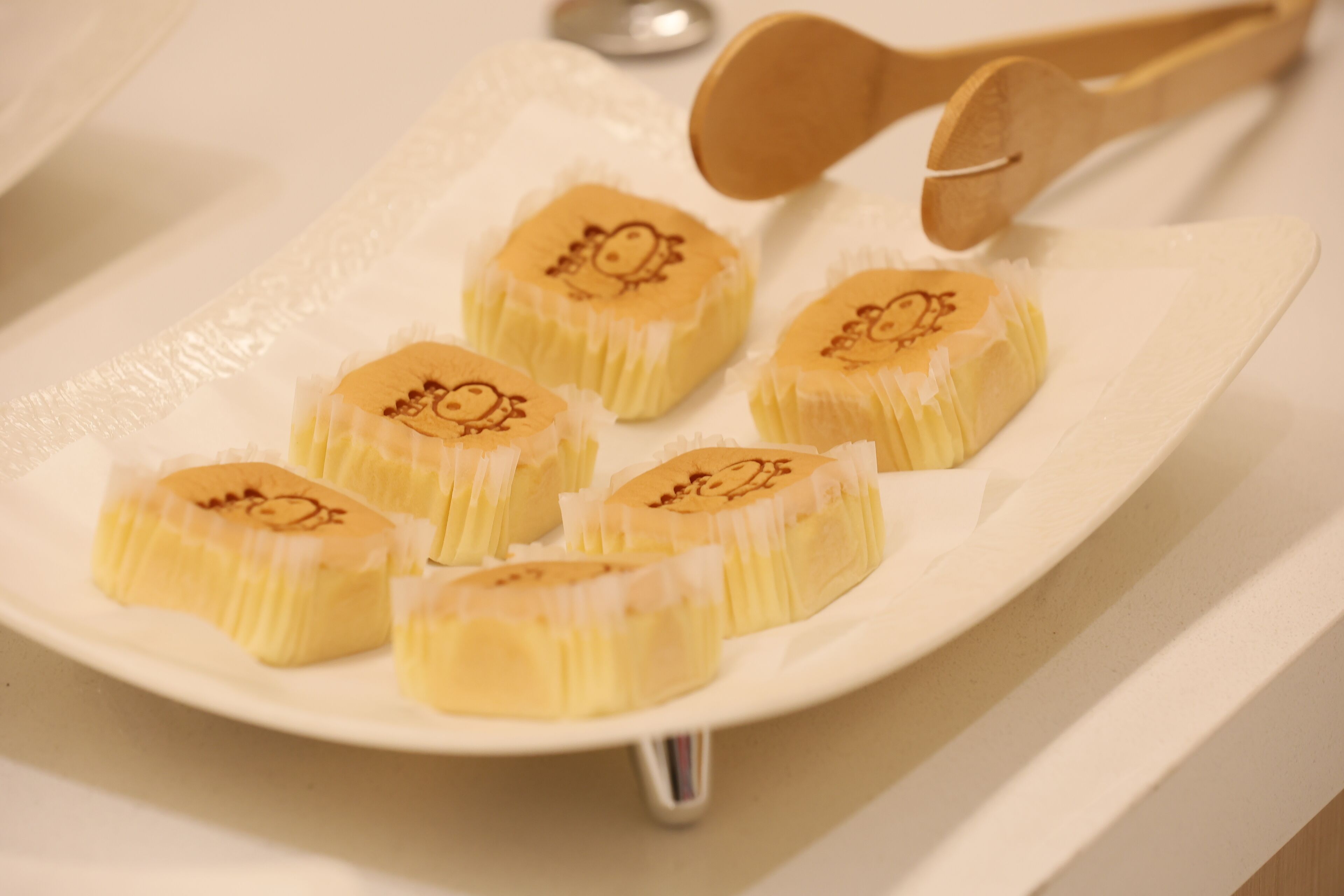Une assiette contenant plusieurs pâtisseries rondes et jaunes, décorées de motifs, posée sur une assiette blanche.