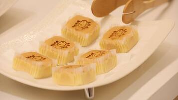 A plate with several round, yellow pastries with a decorative design on top, placed on a white plate.