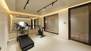 Un gimnasio moderno con equipo de ejercicio, un espejo grande y un puerta corredera de vidrio.