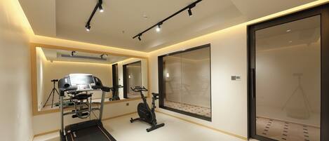 A modern gym with exercise equipment, a large mirror, and a sliding glass door.