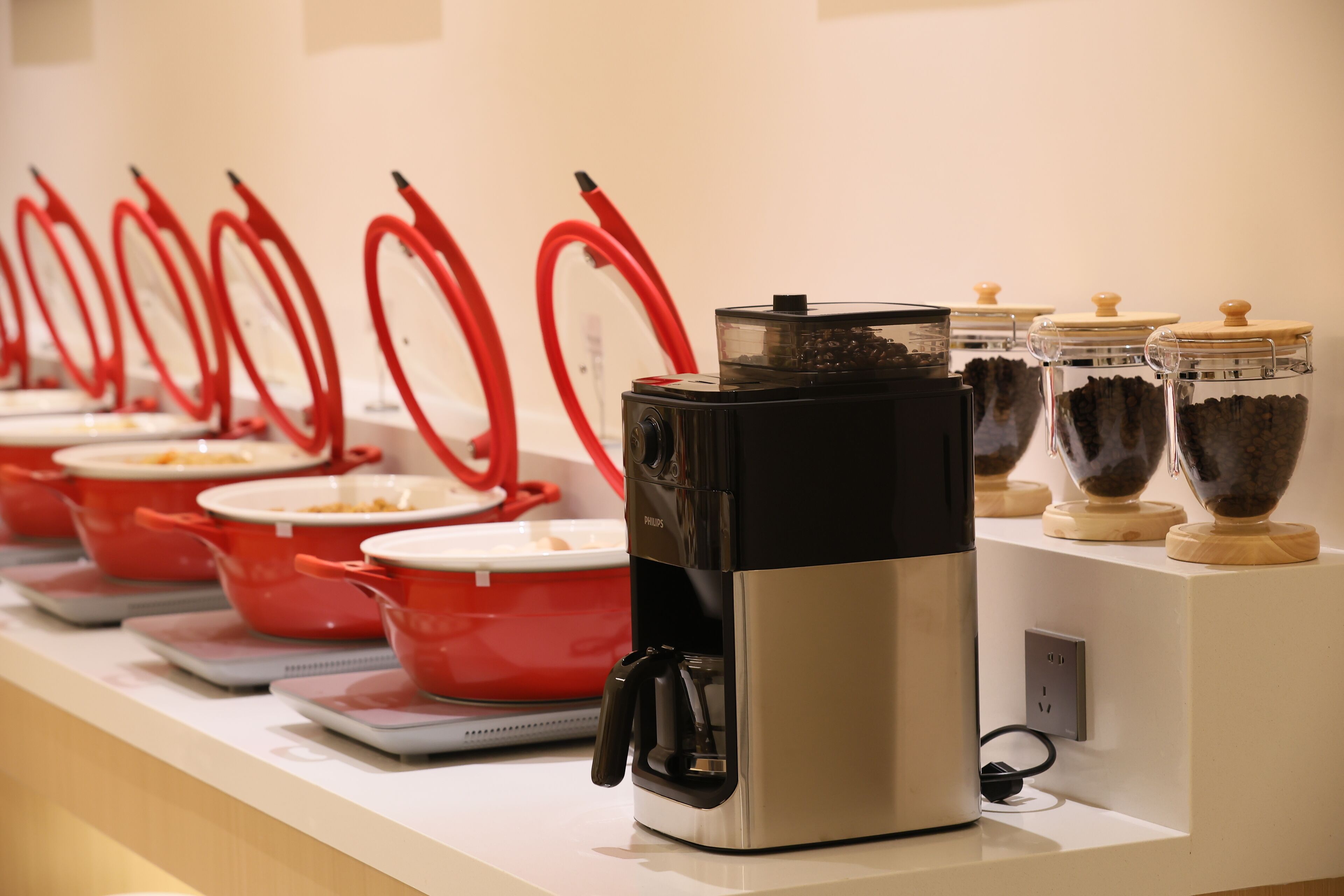 A coffee station with multiple red coffee pots and a coffee machine.