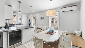 Une cuisine moderne dotée d’un îlot central, de luminaires suspendus et d’un coin repas avec une table ronde et des chaises.