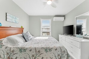 A bedroom with a bed, a dresser, a television, and a ceiling fan.