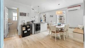 Une cuisine moderne avec un coin repas, un réfrigérateur, un évier et une fenêtre donnant sur l’intérieur.