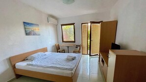 Een slaapkamer met een bed, een bureau, een stoel, een kledingkast en een raam met jaloezieën.