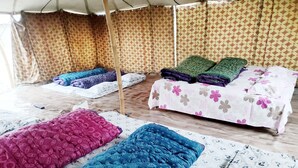 A tent-style room with multiple beds, each with different patterned bedding. - Maha Kumbh Camp (Phulpur)