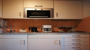 A kitchen with white cabinets, a microwave, a coffee maker, and a fruit bowl. - Holiday Home in Fehmarn near Beach (Fehmarn)