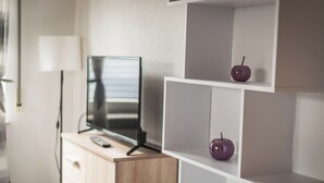 A modern room with a wooden cabinet, a flat-screen TV, and white shelving units.