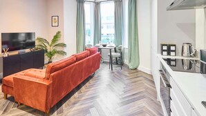A modern living room with a sofa, TV, dining table, and kitchen area. - Host Stay Apartment 1 Upton House (Northampton)
