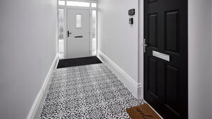 A hallway with patterned flooring, a black door, and a white wall. - Host Stay Apartment 1 Upton House (Northampton)