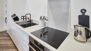 Ett modernt kök med en svart spishäll, en vattenkokare i rostfritt stål och ett knivställ.