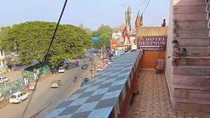 Ein Hotelbalkon mit einem Schachbrettmuster, Blick auf eine belebte Straße und ein Gebäude mit der Aufschrift 'HOTEL DEEPSUN'.