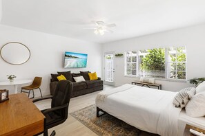 Un dormitorio moderno con cama, escritorio, silla, sofá y televisor.