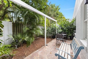 A covered patio area with a bench, a table, and chairs.