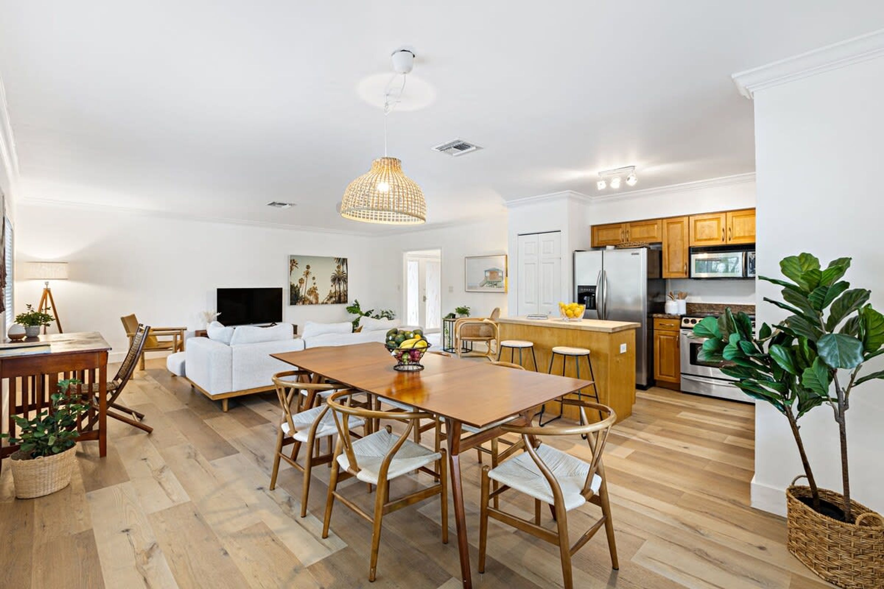 A modern kitchen with wooden cabinets, a central island, and a dining area with a wooden table and chairs.