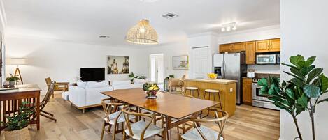A modern kitchen with wooden cabinets, a central island, and a dining area with a wooden table and chairs.