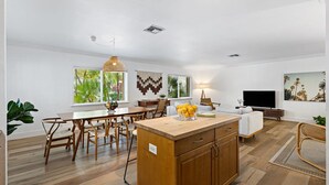 A spacious living area with a wooden dining table, a kitchen island, and a TV. - Spacious Beach Apt in Las Olas Blvd (Fort Lauderdale)