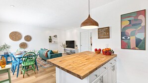 A modern kitchen with a wooden island, white cabinetry, and a hanging pendant light. - Stylish 2 BR Condo - Close to Riverwalk (Fort Lauderdale)