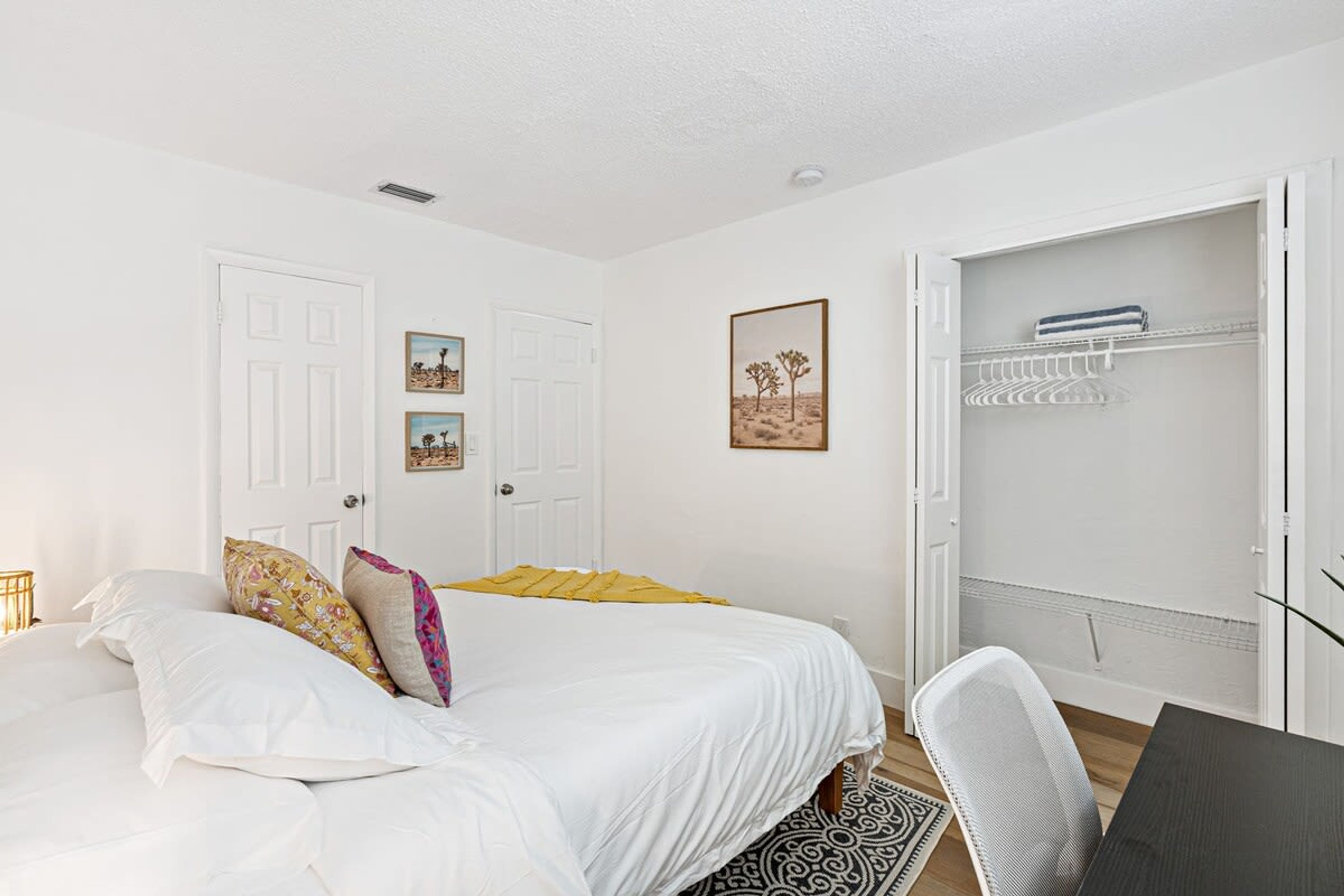 A bedroom with a bed, a desk, and a wardrobe.