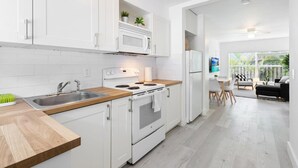 Une cuisine moderne avec des meubles blancs, un four à micro-ondes, une cuisinière et un évier. Il y a également un coin repas avec une table et des chaises.