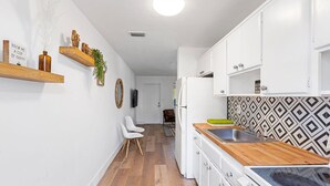 A narrow kitchen with white cabinets, a wooden countertop, and a patterned backsplash. - The Perfect Escape Lake Ridge (Fort Lauderdale)