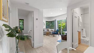 Un intérieur moderne avec un plancher en bois, une chaise blanche, une plante et une vue sur un balcon agrémenté de verdure.