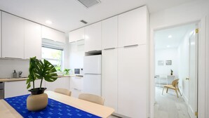 Une cuisine moderne avec des meubles blancs, une nappe bleue et une plante en pot.