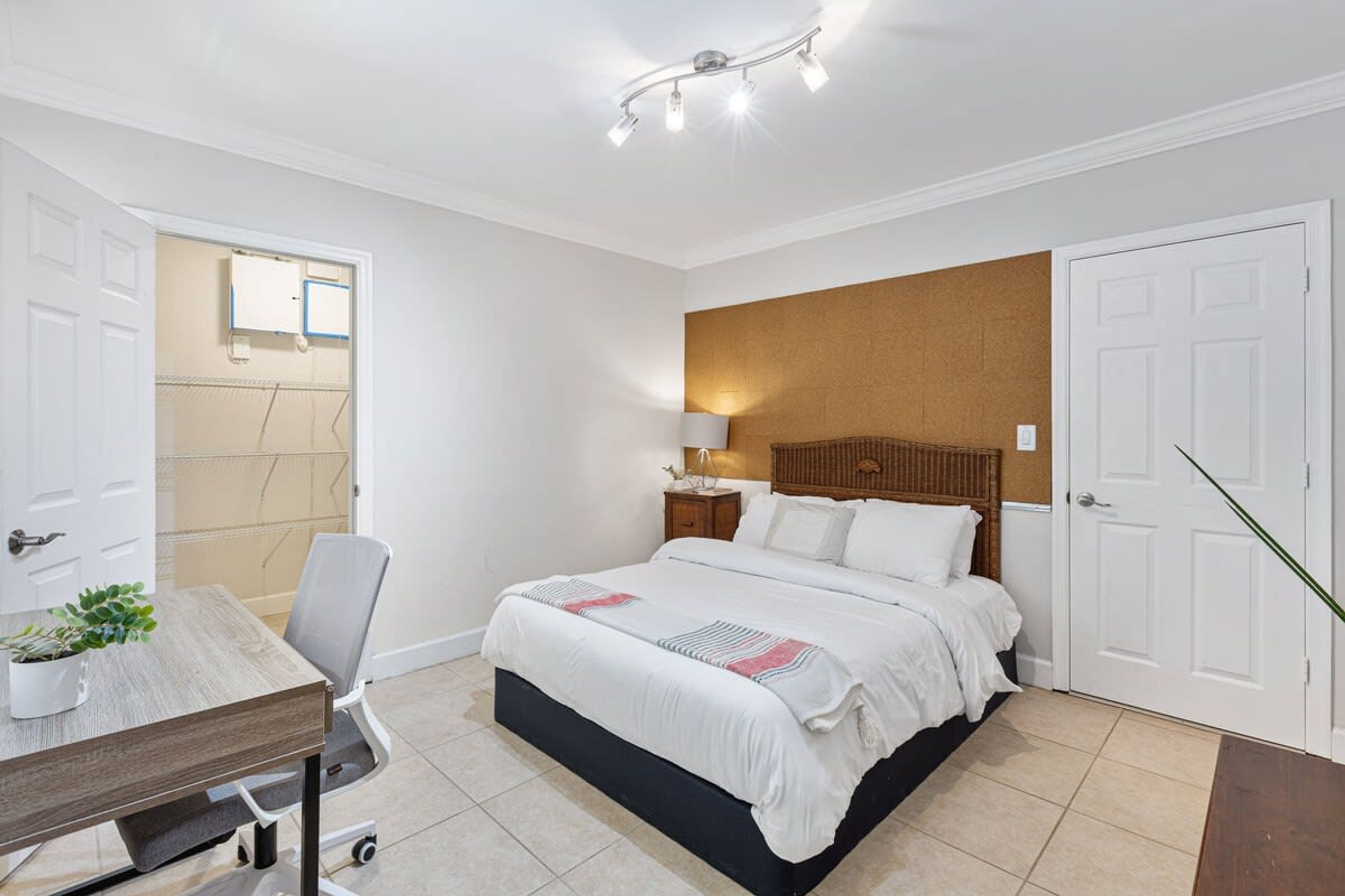 Un dormitorio con cama, mesita de noche, lámpara y un escritorio con silla.