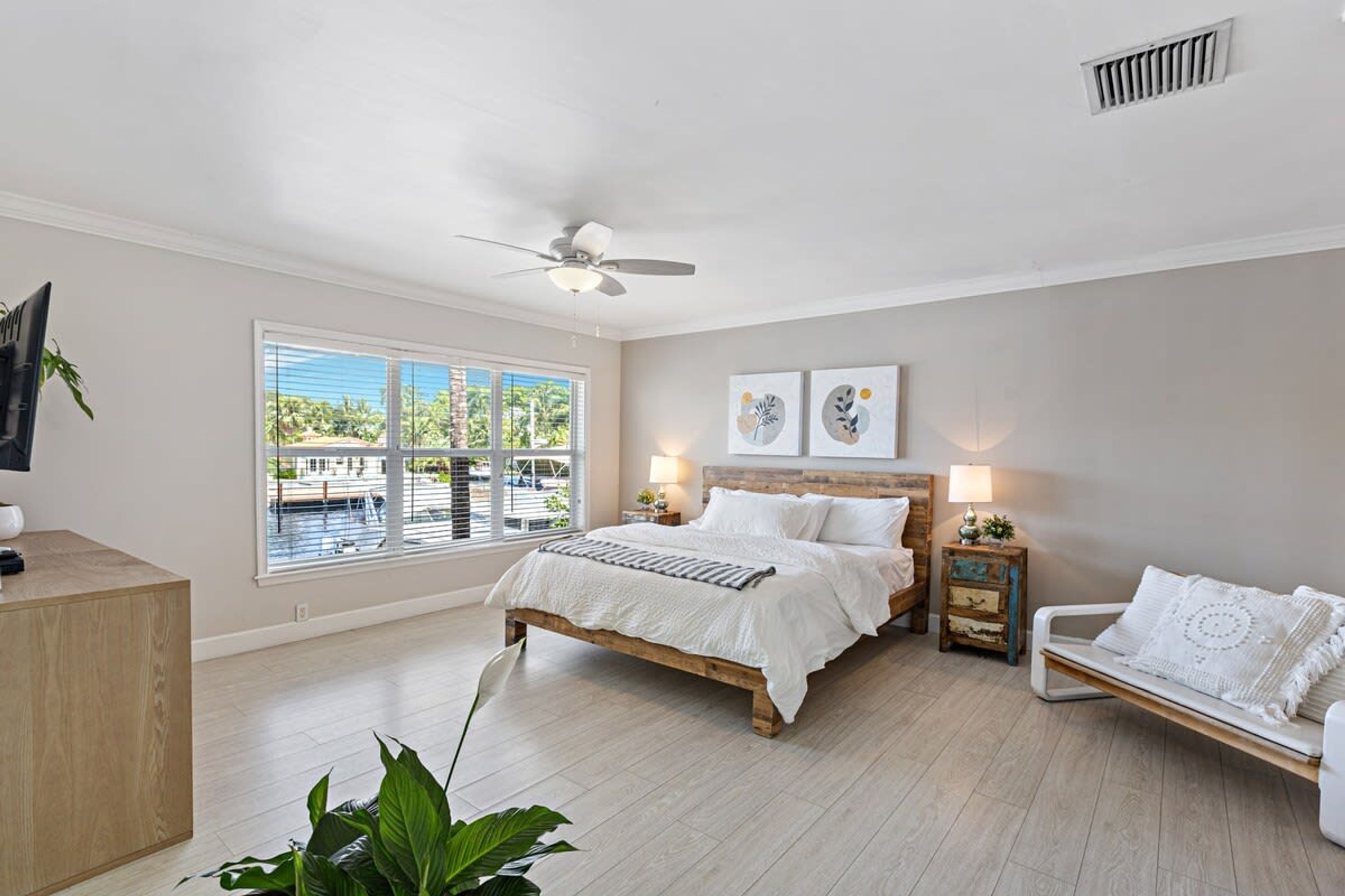 A bedroom with a bed, bedside tables, a desk, a chair, and a large window.
