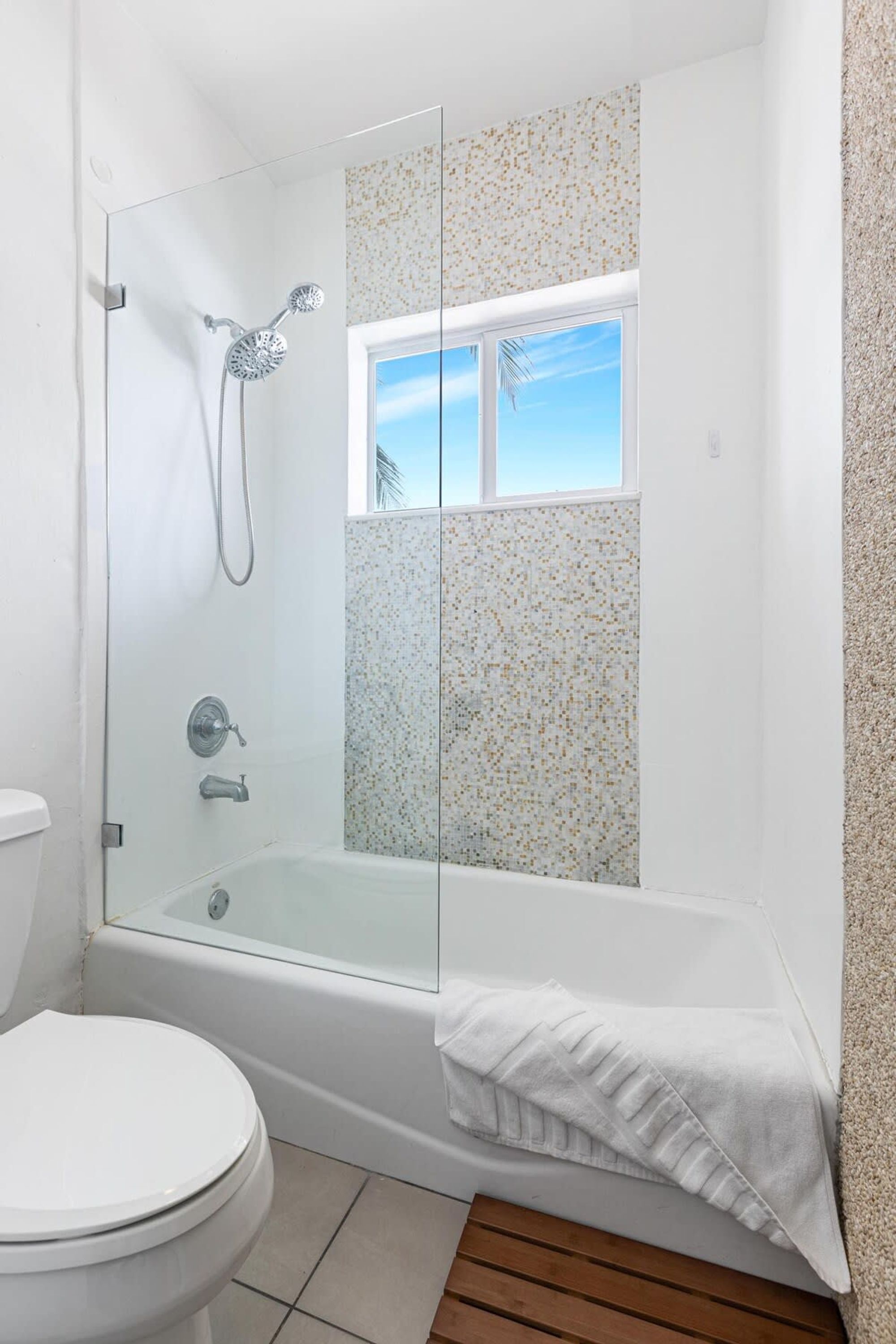 A bathroom with a glass-enclosed shower, a bathtub, and a toilet.