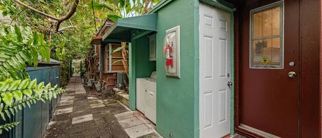 Un estrecho callejón con un edificio verde, una puerta marrón y un extintor en la pared.