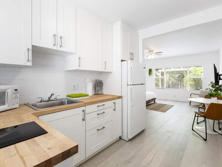 Une cuisine moderne avec des meubles blancs, un four à micro-ondes et un évier. On y trouve également un coin repas avec une table et des chaises.