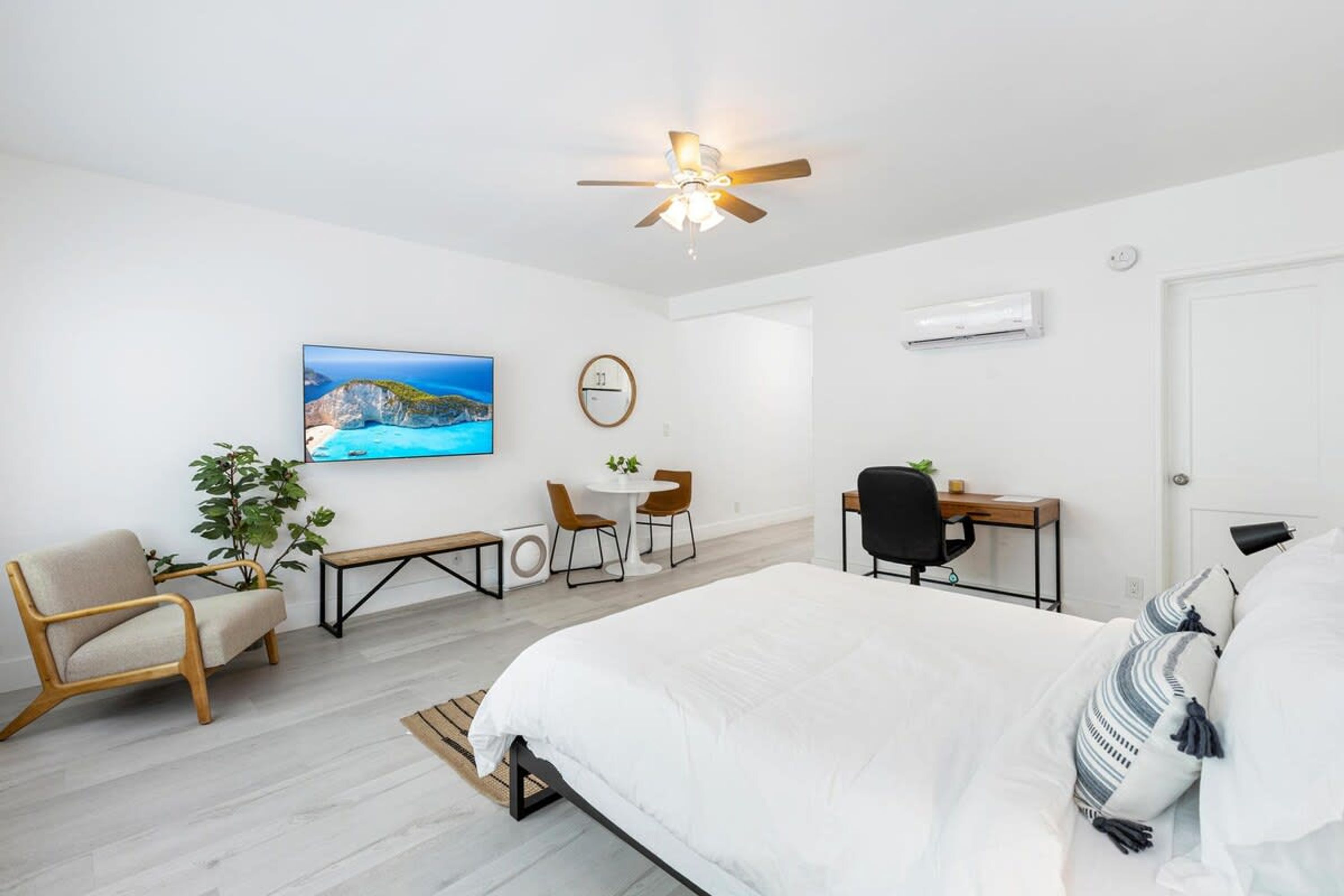 Une chambre moderne comprenant un lit, un bureau, une chaise, une petite table et un téléviseur.