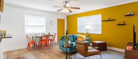 A compact living space with a dining area, a sofa, a ceiling fan, and a small table with chairs.