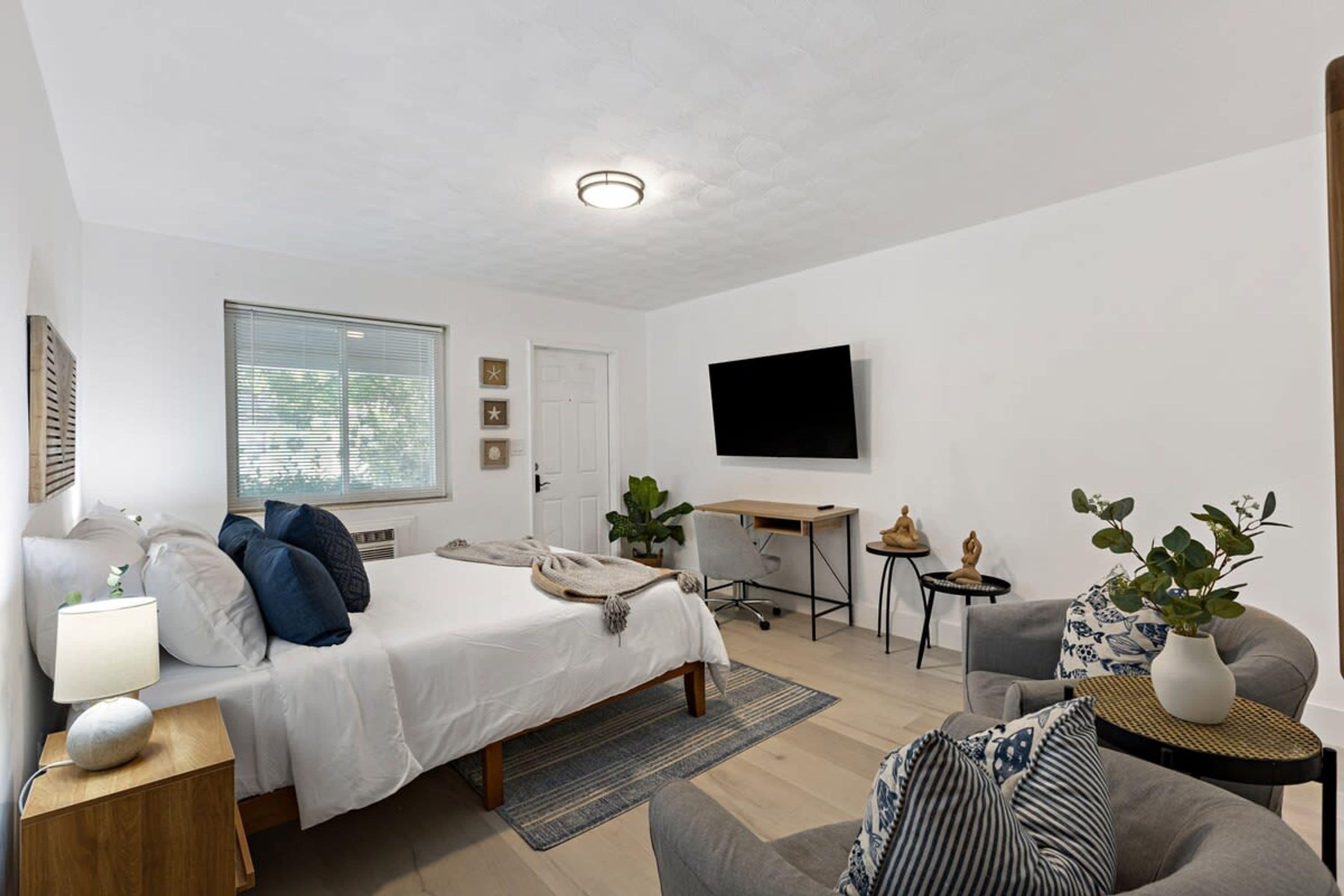 Een moderne hotelkamer met een bed, bureau en zithoek.