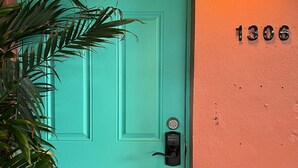 A turquoise door with a keypad lock, a wall-mounted light, and the number 1306 on the wall. - Charming Cozy Studio Lake Ridge (Fort Lauderdale)
