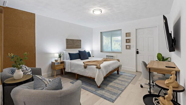 A modern bedroom with a bed, bedside tables, a desk, and a chair. - Charming Cozy Studio Lake Ridge (Fort Lauderdale)
