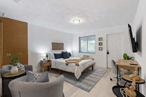 A modern bedroom with a bed, bedside tables, a desk, and a chair. - Charming Cozy Studio Lake Ridge (Fort Lauderdale)