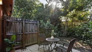 A patio with a wooden fence, a round table, and two chairs. - Charming Cozy Studio Lake Ridge (Fort Lauderdale)