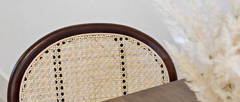 A wooden chair with a woven backrest and a table in front.