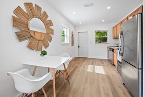 Modern kitchen with a round mirror, dining table, and stainless steel refrigerator.