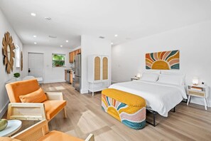 Relax in a serene space with a large bed, armchair, and wicker chair.